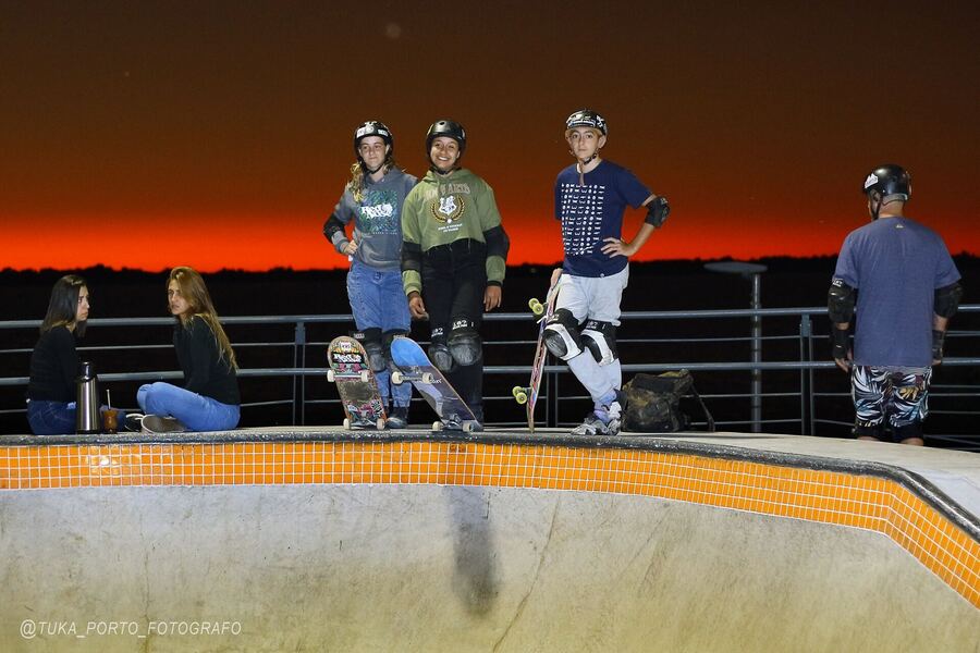 Grupo de skatistas reunido na pista no fim da tarde