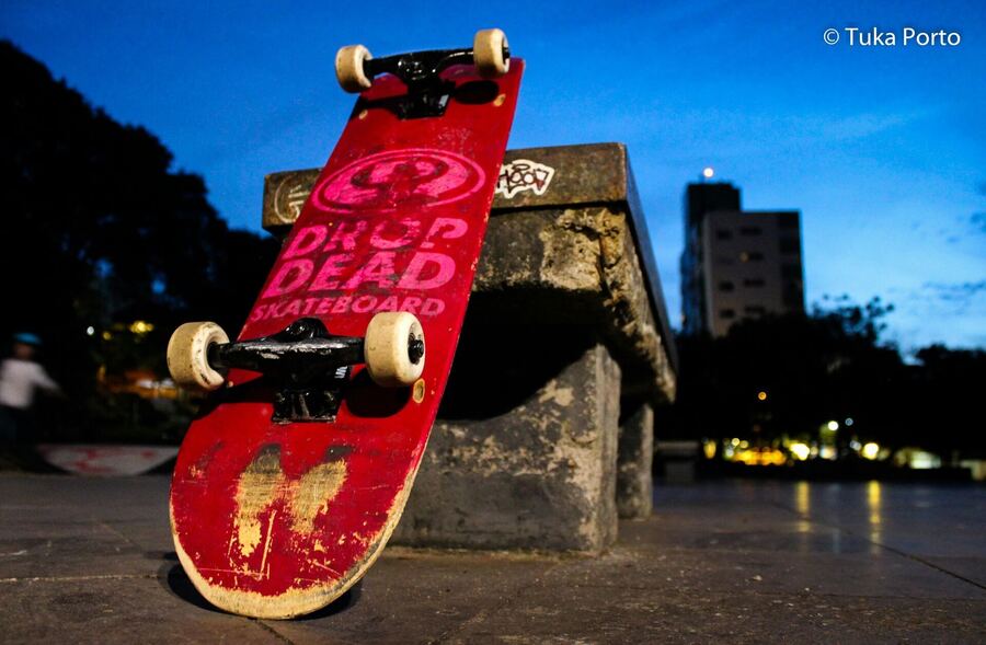 O skate encostado, com a cidade no fim do dia
